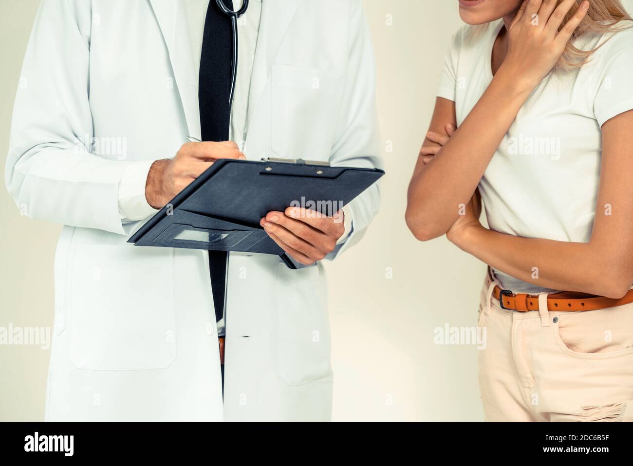 Männlicher Arzt und Patientin mit Dokumenten der Patienten Gesundheit Aufzeichnung sind in Konversation im Krankenhaus. Gesundheitswesen und medizinische Betreuung. Stockfoto