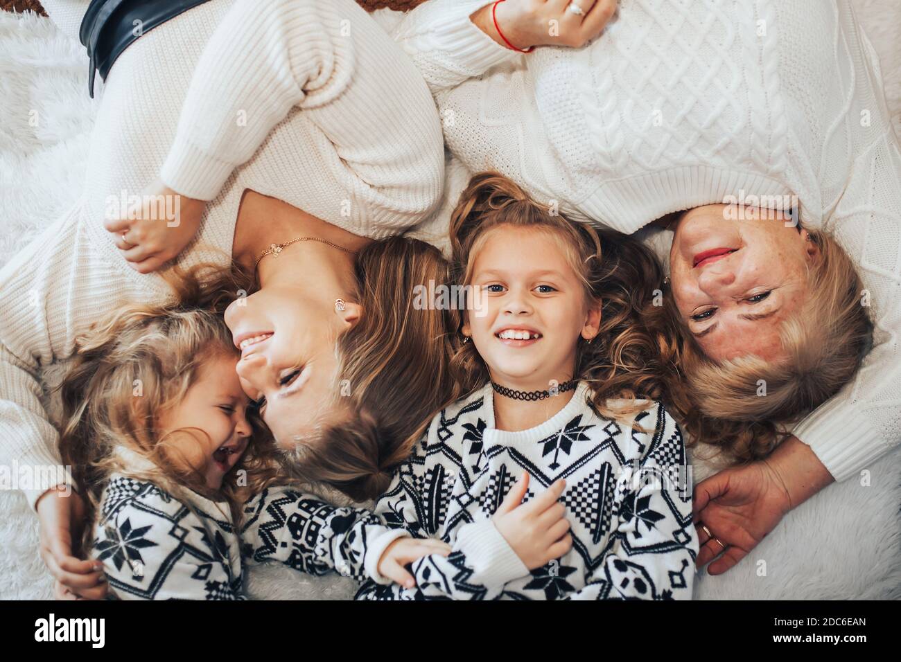 Kinder mit Mutter und Großmutter liegen auf einem großen Bett. Große freundliche Familie. Generation von Frauen. Stockfoto