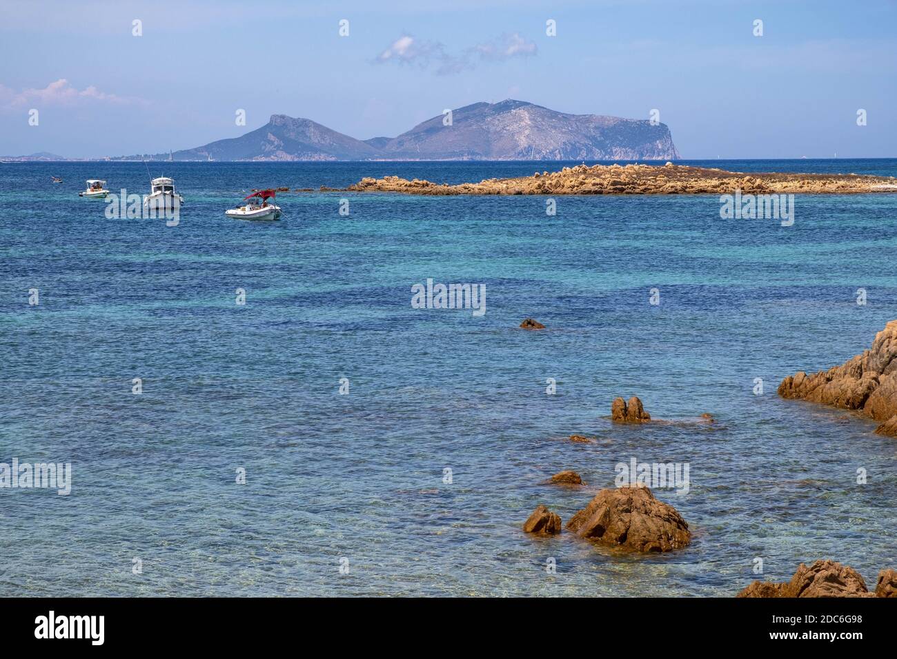 Tavolara, Sardinien / Italien - 2019/07/18: Tyrrhenisches Meer mit Yachten vor der Küste Isola Tavolara mit Capo Figari Kap, Monte Ruju Gipfel und Golfo Ar Stockfoto