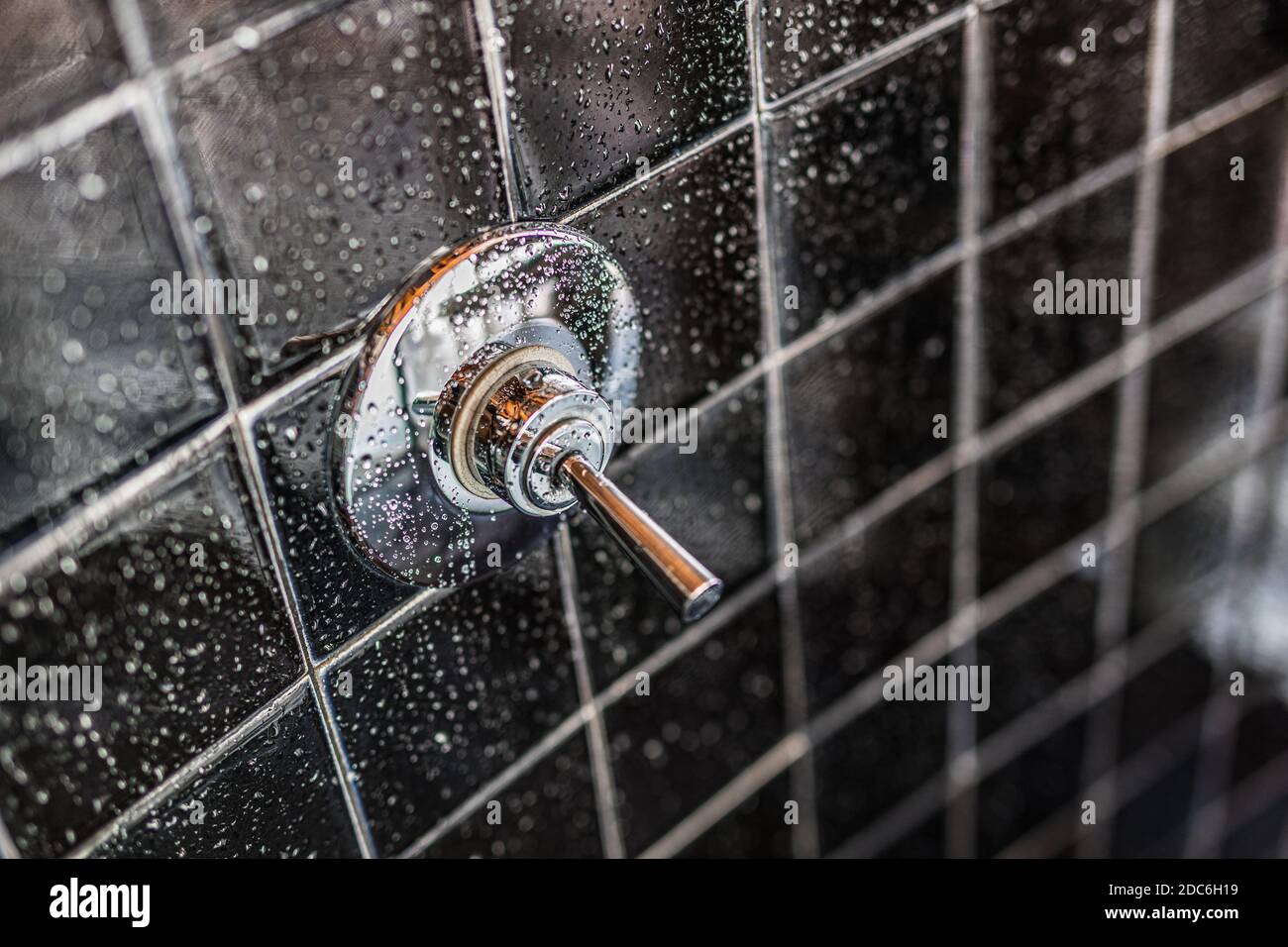 Nahaufnahme der modernen schwarzen Dusche Badewanne mit blauen Vorhängen im Badezimmer in Modell Haus, Wohnung oder Haus, Fliesen, Wasserhahn, Tropfen Wasser Stockfoto