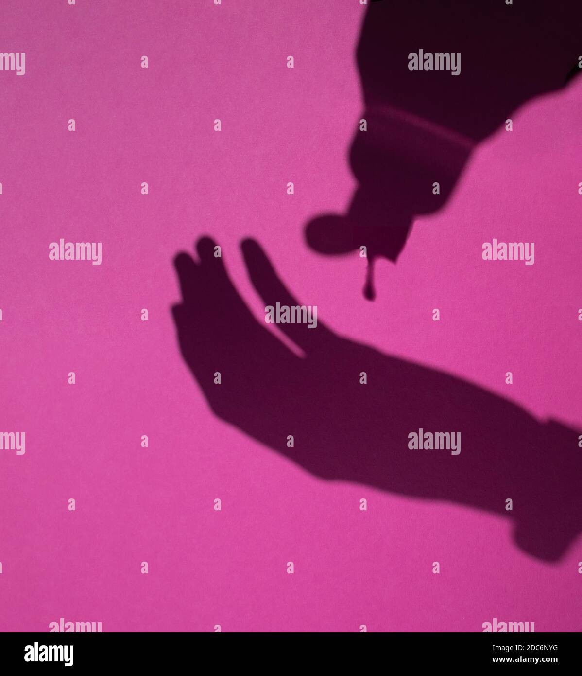 Selektive Fokus der Schatten der Hände Gießen hydroalkoholischen Desinfektionsmittel Gel für die Prävention von Covid19 auf einem rosa Hintergrund, Public Health Pandemi Stockfoto