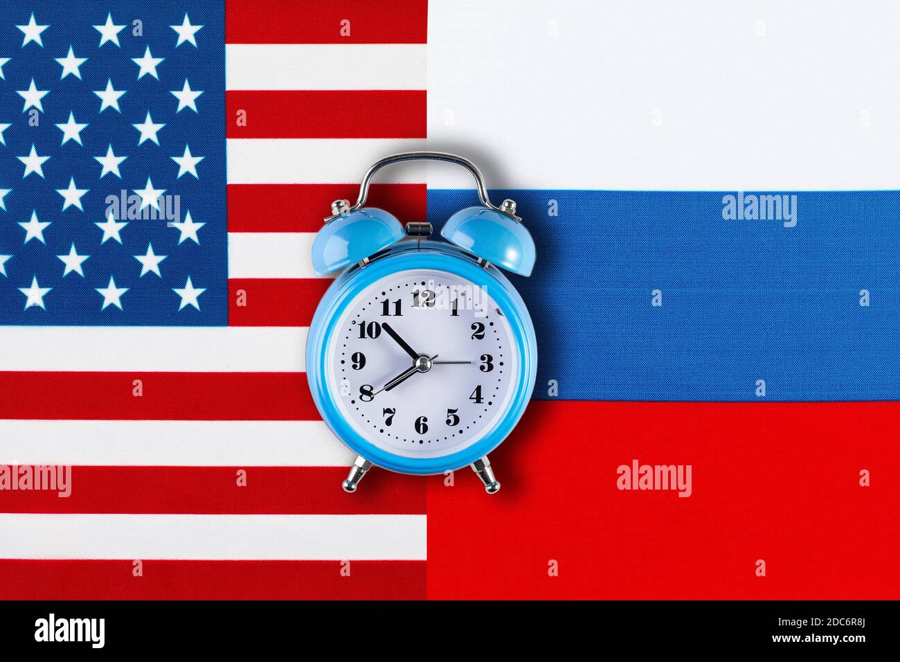 Russische und amerikanische Flaggen und die Uhr als Symbol der politischen Beziehungen. Kreative Draufsicht flat lay von Russland und USA Flagge Wecker. Konzept von Stockfoto