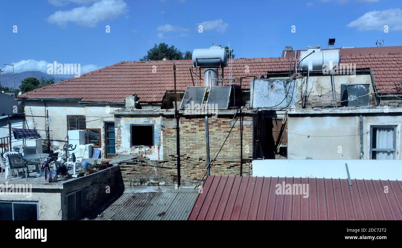 Alte, leicht verfallene Dächer in der südgriechischen Altstadt Nicosia mit zwei solarthermischen Warmwassersystemen Stockfoto