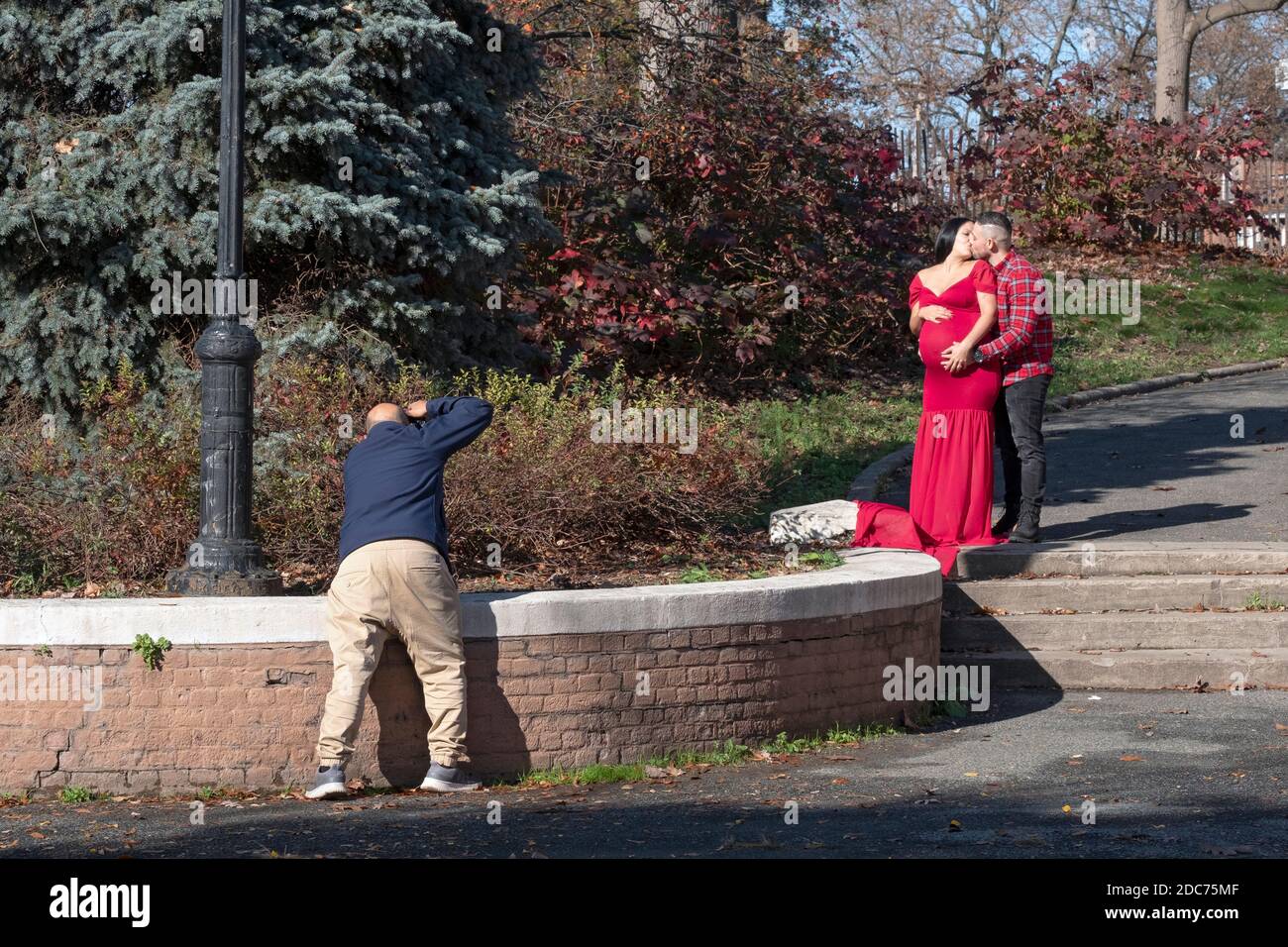 Ein Ehemann und eine schwangere Frau beauftragen ein Fotoshooting anlässlich ihrer Schwangerschaft. An einem milden Herbsttag in Queens, New York City. Stockfoto
