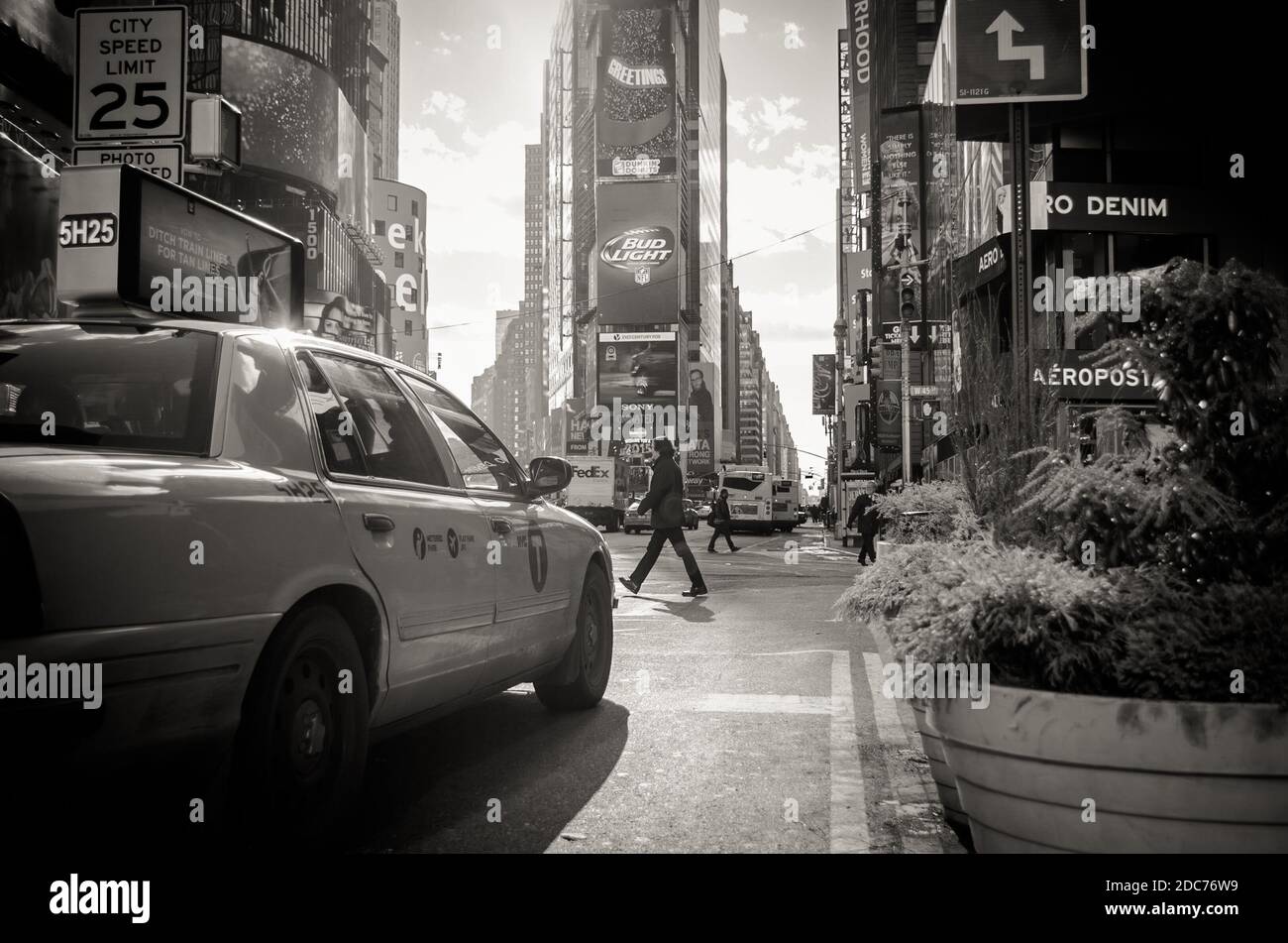 Manhattan Times Square Blick in Schwarz und Weiß. Ein Mann überquert die Straße vor einem Taxi. Bezirk voll von LED-Bildschirmen und Reklameanzeigen. Stockfoto