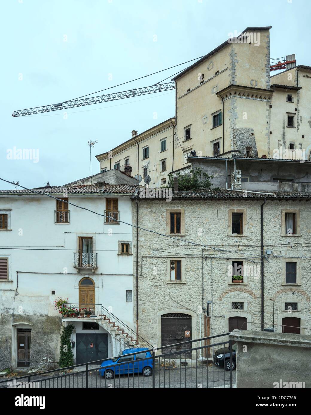 Stadtbild mit Kran von Erdbeben Wiederherstellung Baustelle drohende aus alten beschädigten Häusern auf Hügel historischen Dorf, in helles Licht auf Fon geschossen Stockfoto