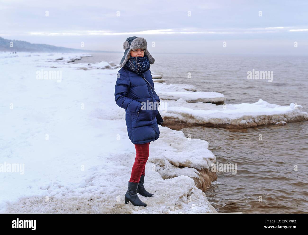 Frau, die am verschneiten Ufer der Ostsee steht. Stockfoto