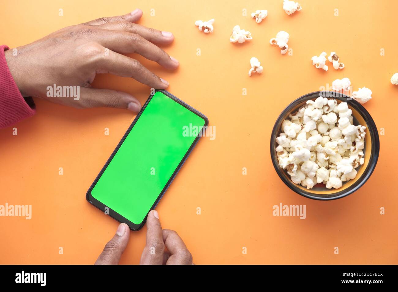 Mann Hand mit Smartphone und essen Popcorn Stockfoto