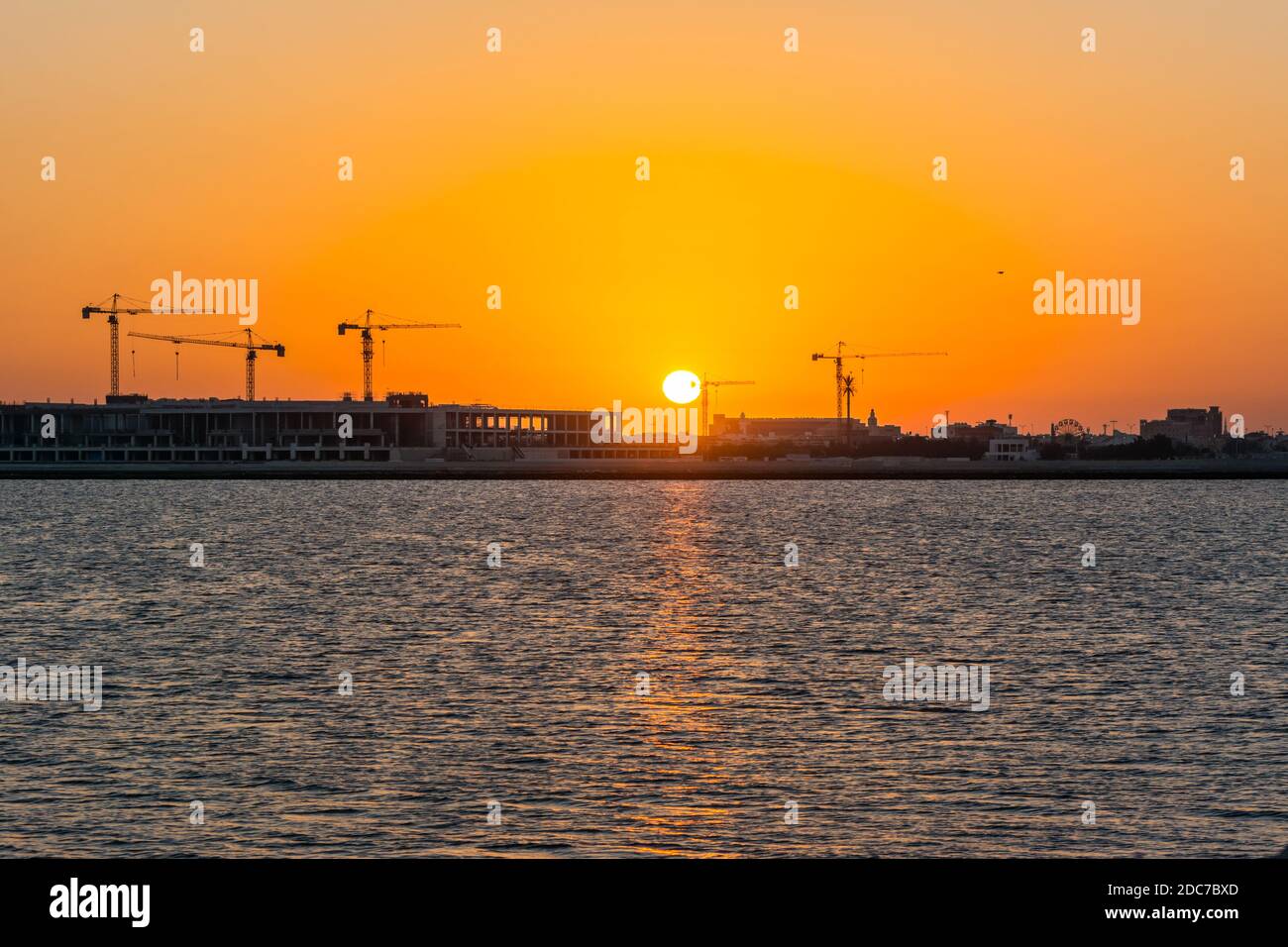 Landschaft der Sonne steigt über der Baustelle mit Kran im Meer am Morgen in Dammam, Königreich Saudi-Arabien Stockfoto