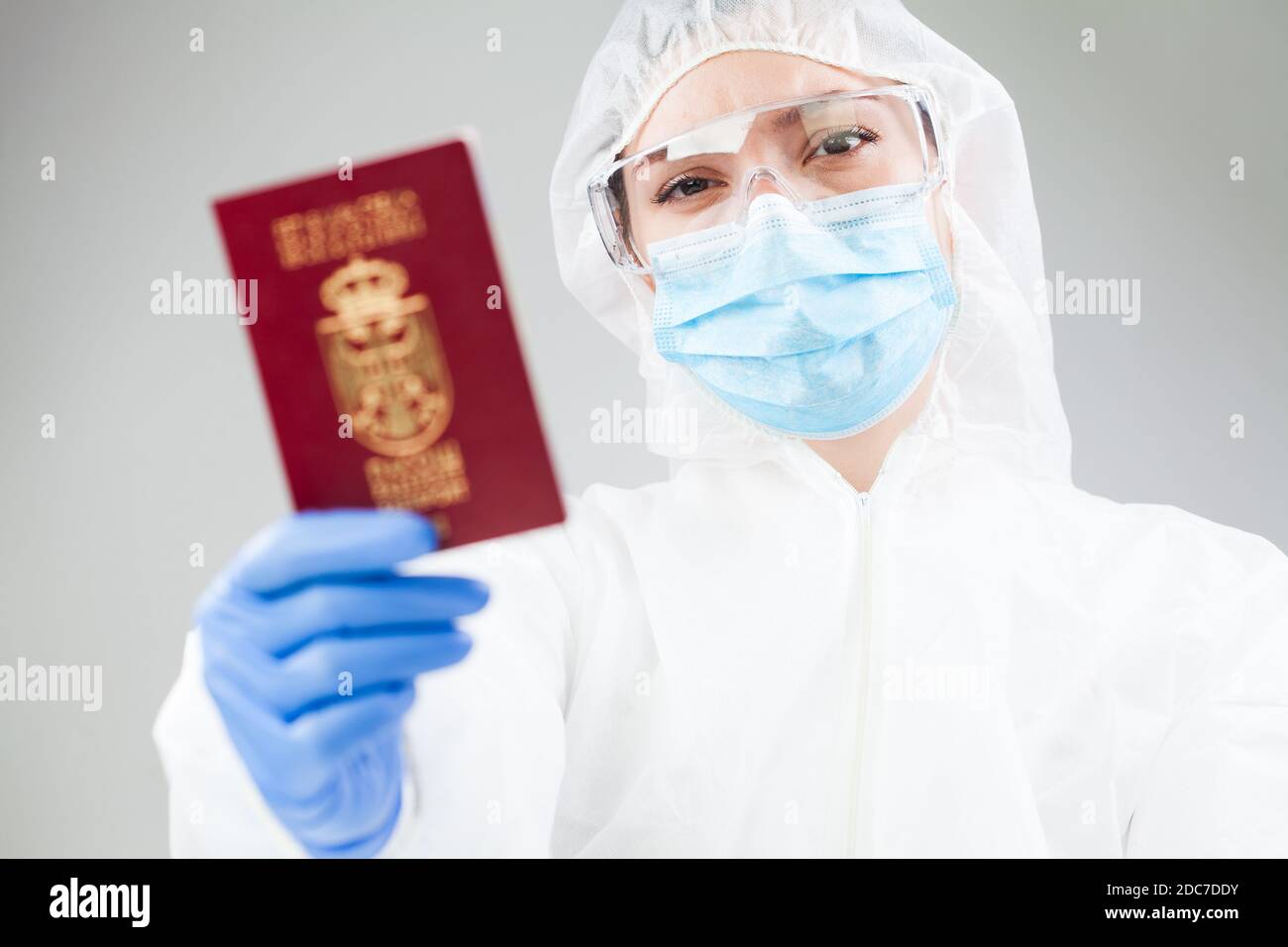 Medizinisches medizinisches Personal in voller persönlicher Schutzausrüstung mit roter Hand Reisepass, Coronavirus COVID-19 Immunität Pass/risikofreies Zertifikat Stockfoto