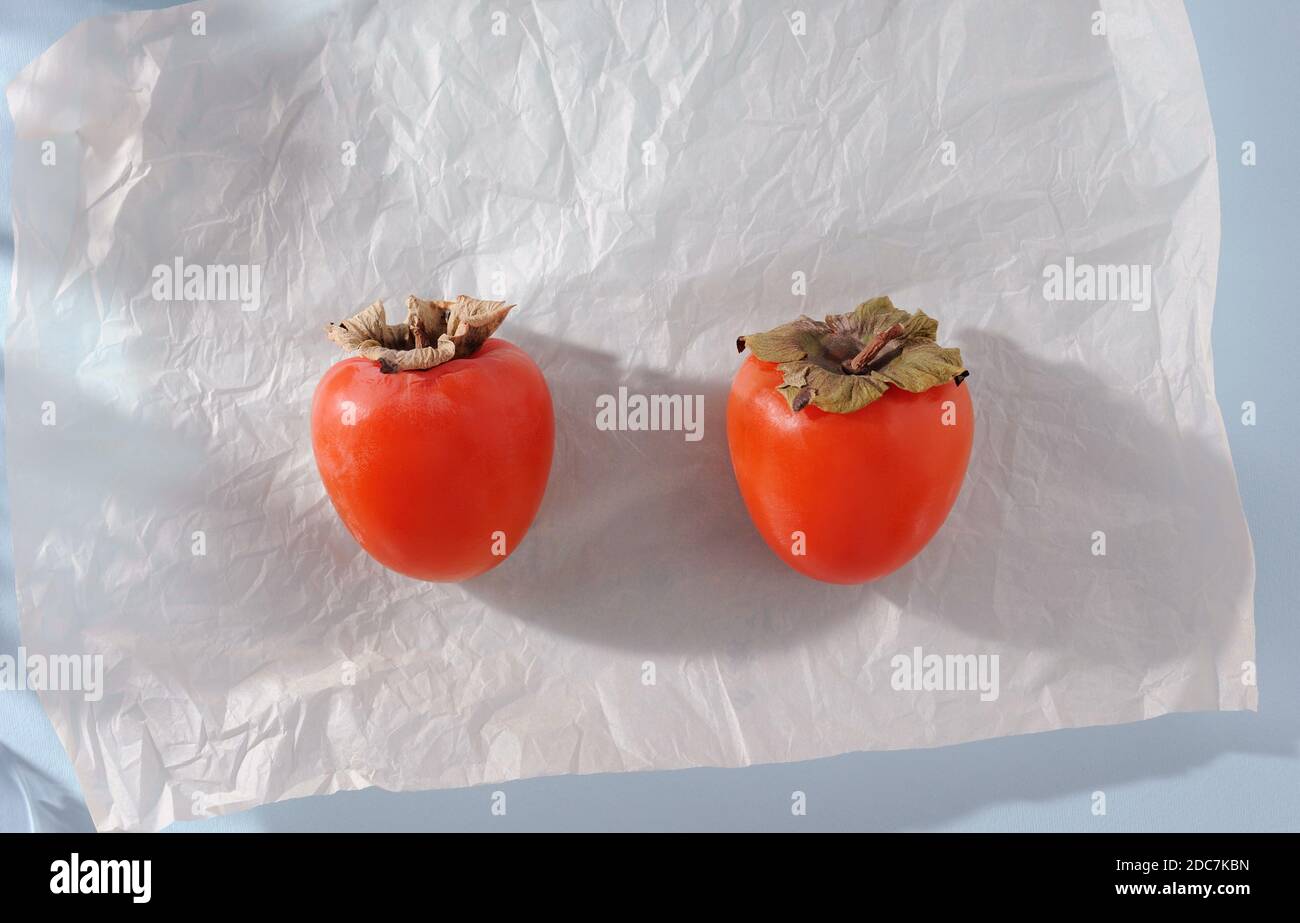 Kreativer Hintergrund mit Kaki und Schatten auf dem Hintergrund. Persimmon eine essbare Frucht mit sehr süßem Fleisch. Food-Konzept. Flach liegend mit Kopie Stockfoto