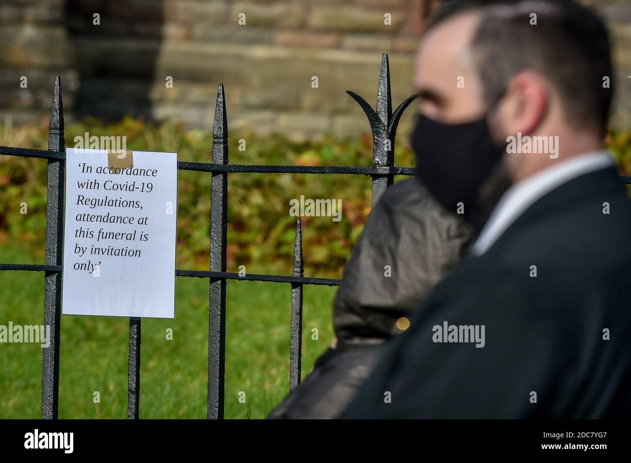 Ein Trauerdirektor trägt ein Gesicht mit einem Schild, das bei der Beerdigung von Gladys, Dean und Darren Lewis in der St. Peter's Church in Pentre, Südwales, auf die Vorschriften für die Begräbnisfeier hinweist. Frau Lewis und ihre beiden Söhne starben alle innerhalb von fünf Tagen an Covid-19. Stockfoto