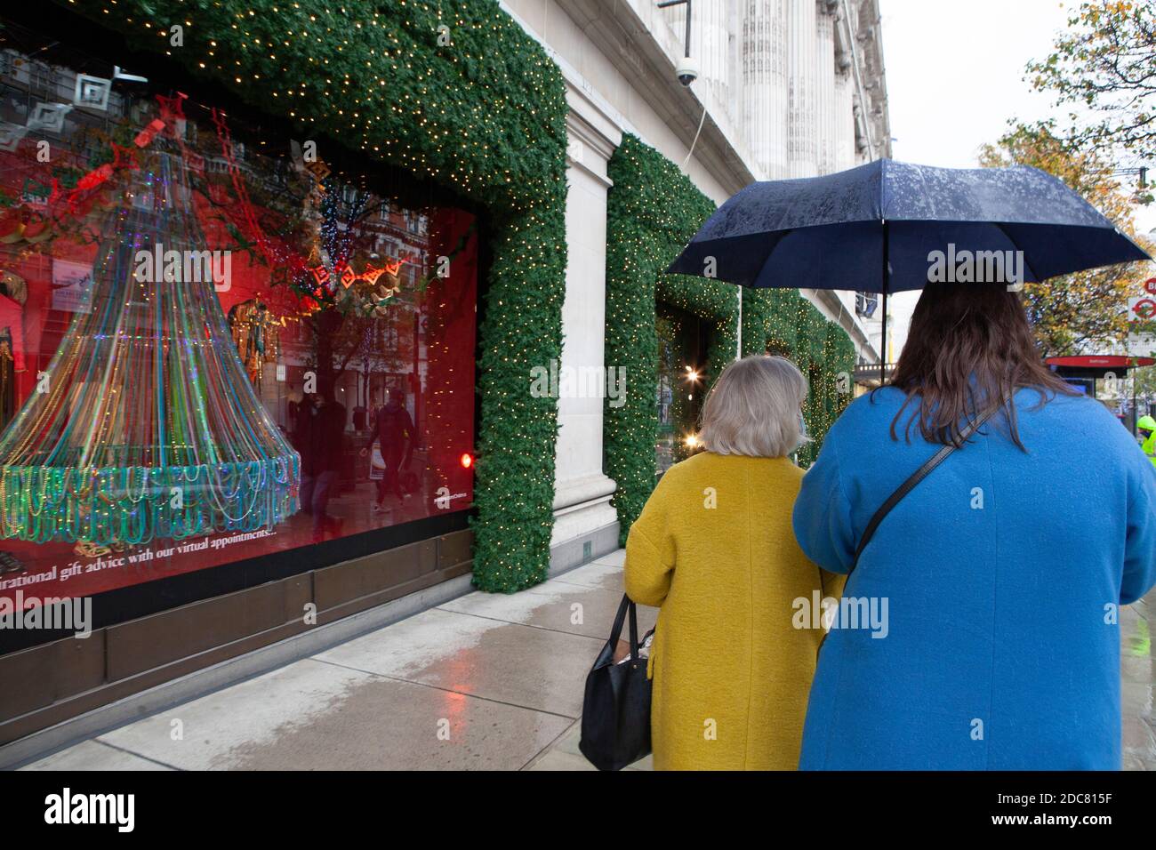 London, Großbritannien, 19. November 2020: Trotz Englands Lockdown und regnerischem Wetter gehen manche Leute zum Schaufensterbummeln oder benutzen Click and Collect im Londoner West End. Die Fenster des Kaufhauses Selfridges sind eine Attraktion für Passanten. Anna Watson/Alamy Live News Stockfoto