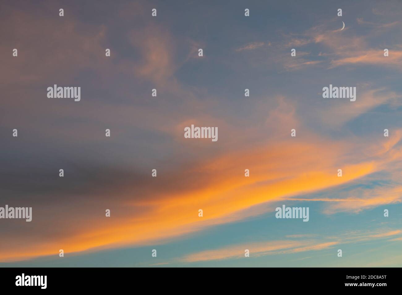 Hohe Wolken (Cirrus) und Halbmond bei Sonnenuntergang Stockfoto