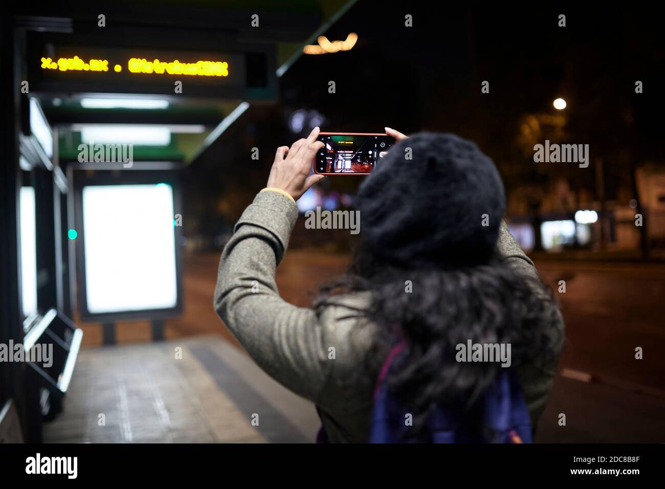 Frau, die nachts in einer Bushaltestelle Fotos gemacht hat Stockfoto