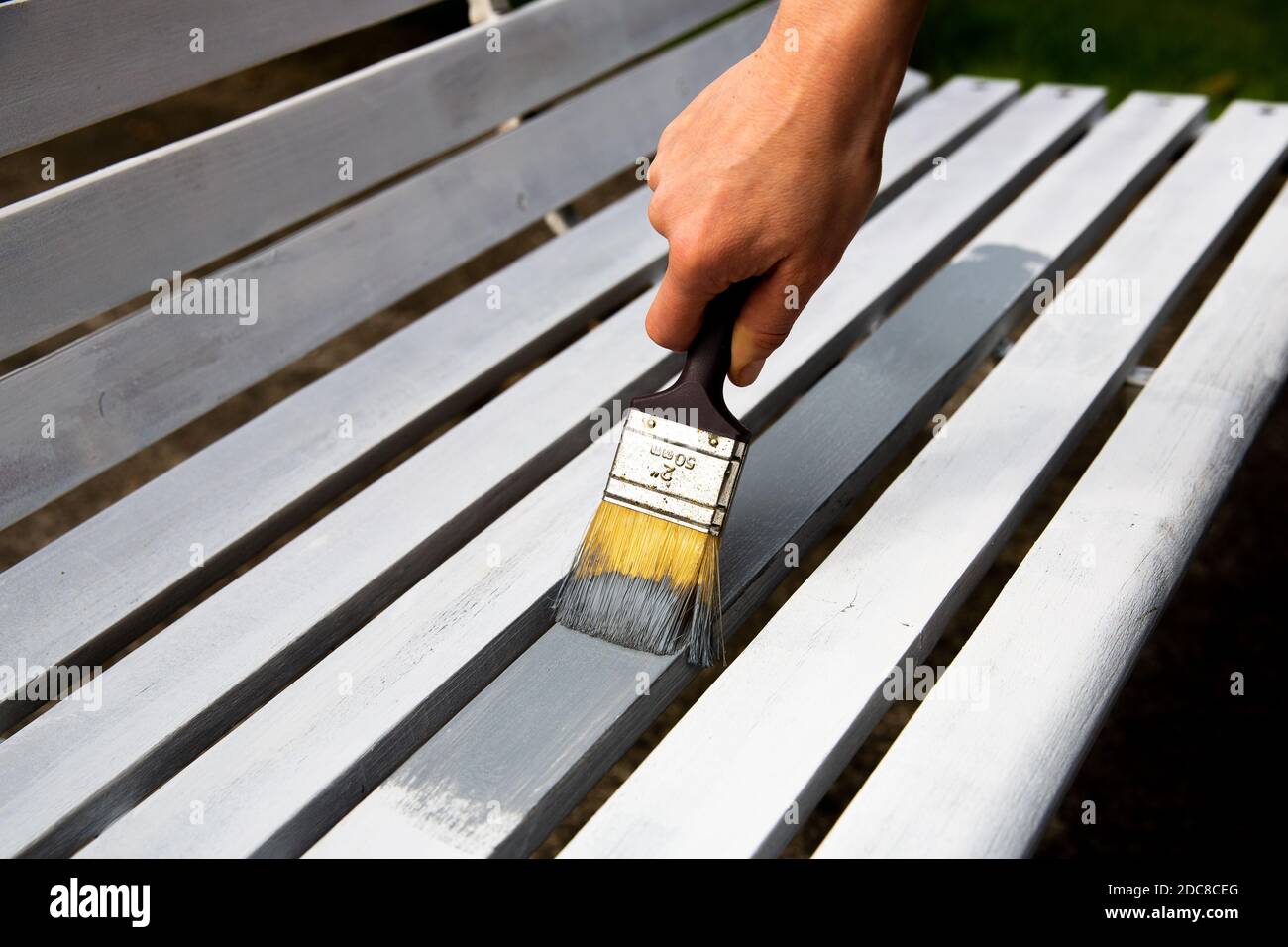 Prozess der Handbemalung von weißen Holzbrettern mit grauer Farbe mit Malpinsel. Stockfoto