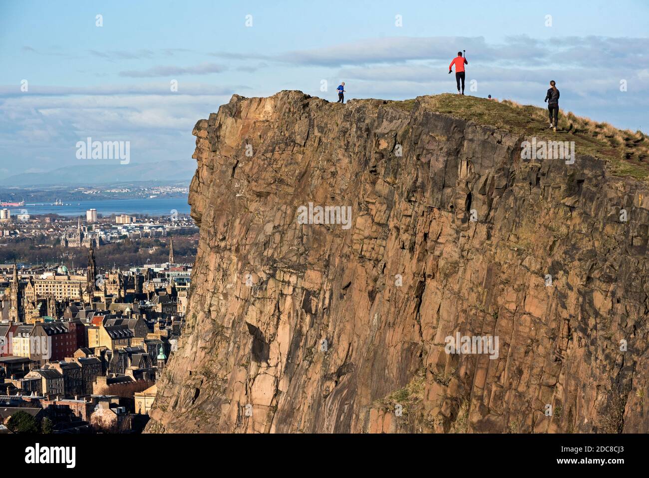 Läufer, die die November-Sonne auf den Salisbury Crags genießen, Edinburgh, Schottland, Großbritannien. Stockfoto