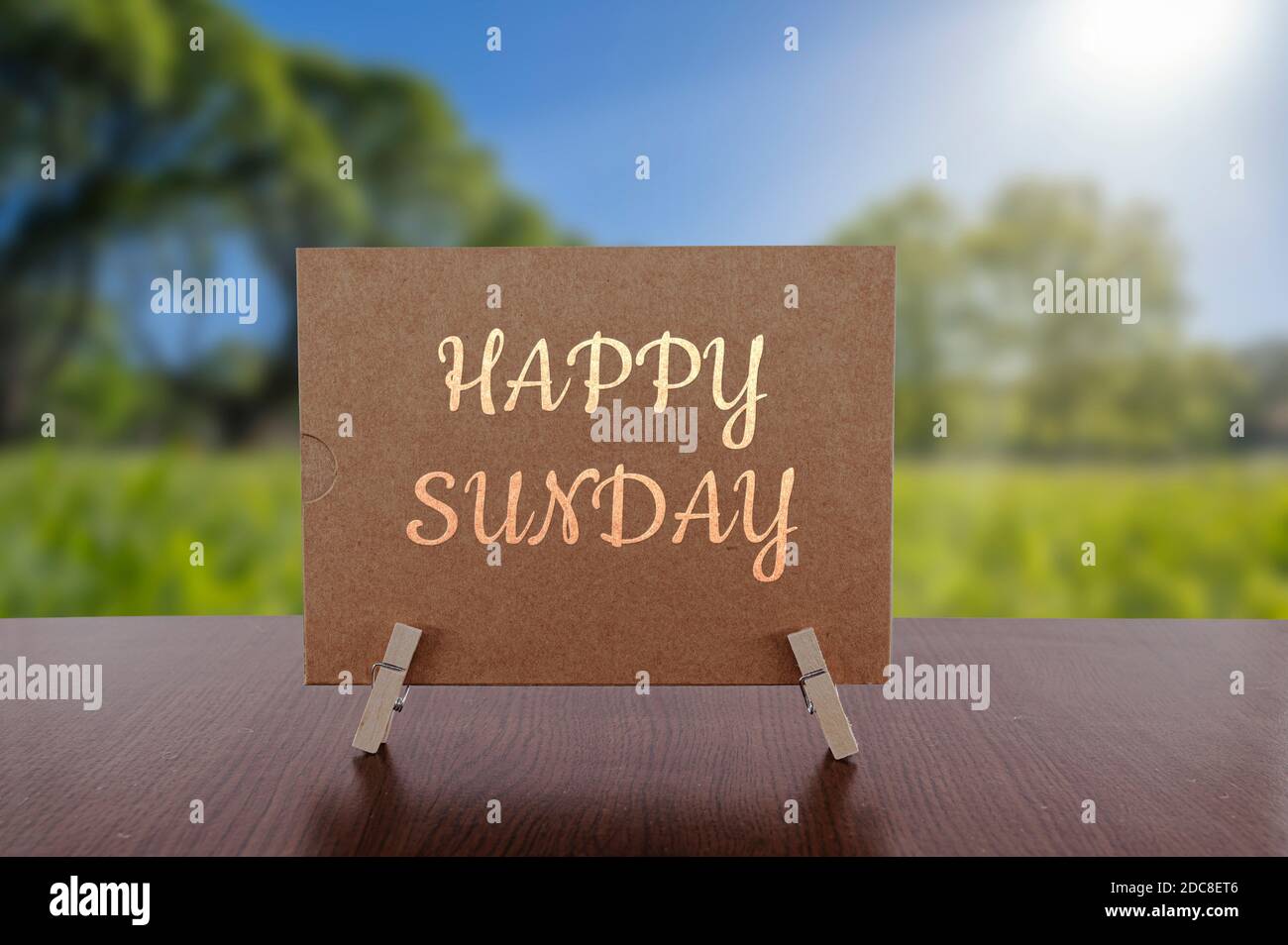 Happy Sunday Karte auf dem Tisch mit sonnigen grünen Wald Hintergrund. Stockfoto