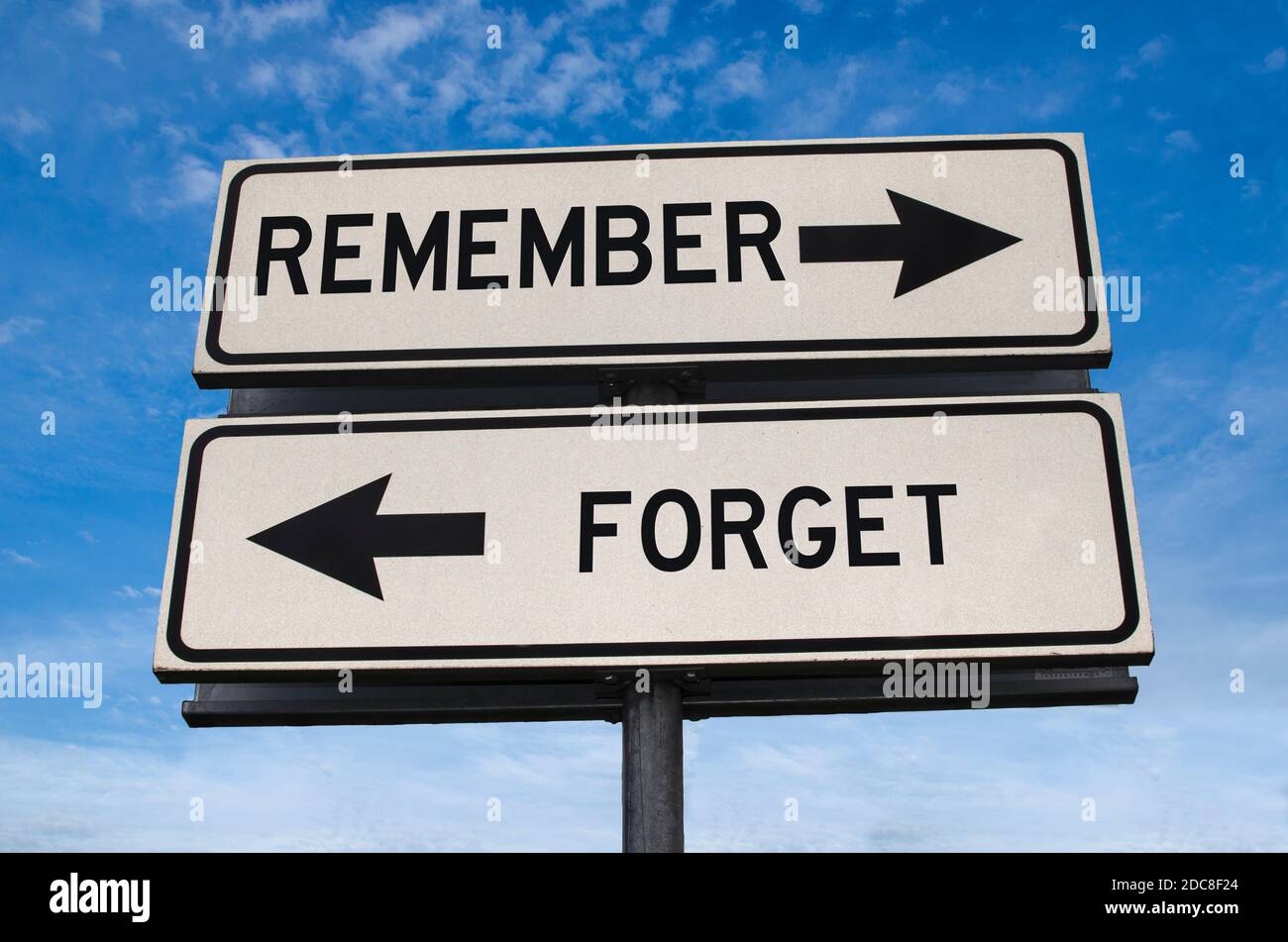 Denken Sie daran oder vergessen Sie das Straßenschild. Weiße zwei Straßenschilder mit Pfeil auf Metallmast mit Wort. Richtungsstraße. Kreuzung Straßenschild, Zwei Pfeil. Blau s Stockfoto
