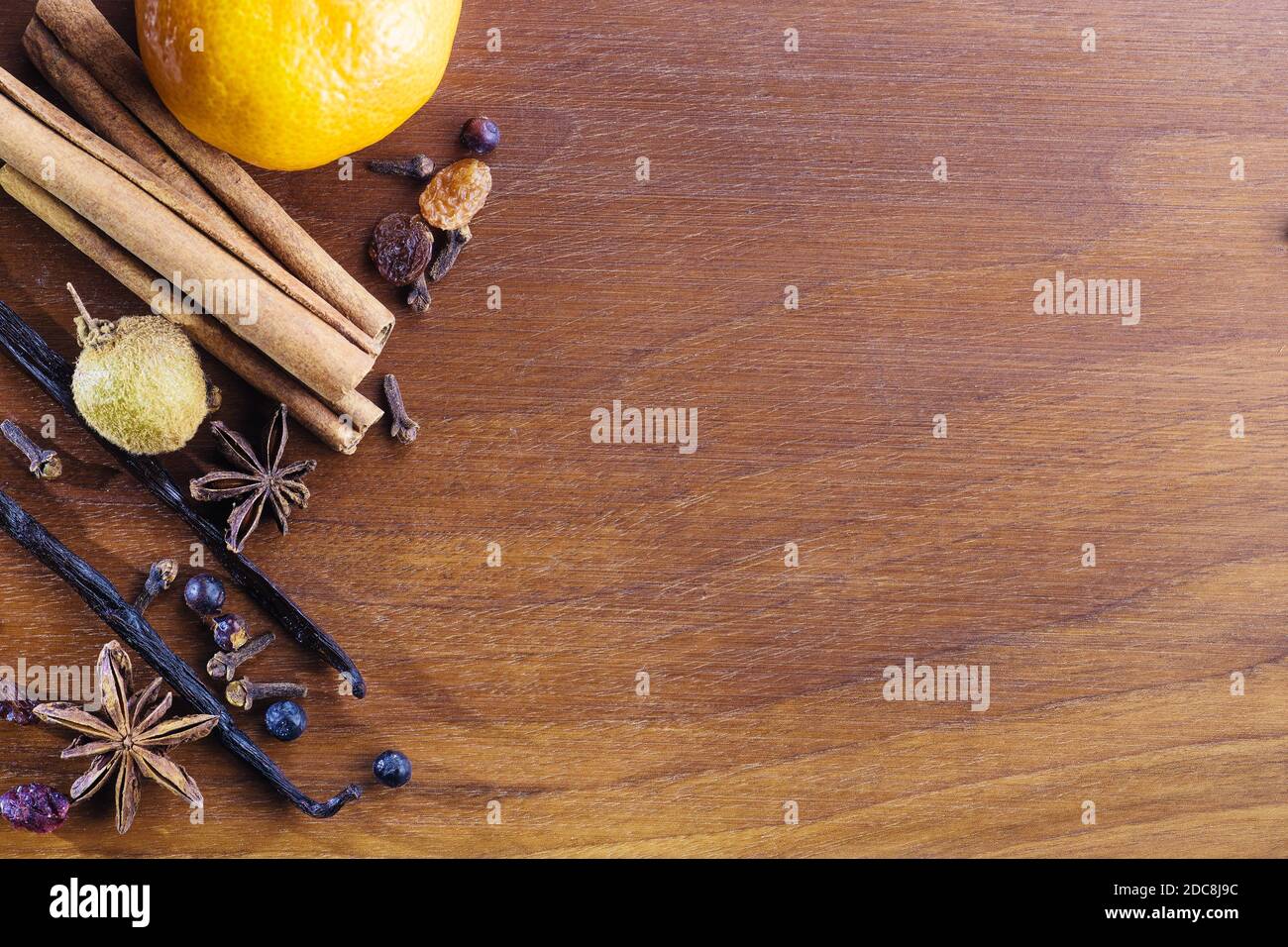 Nahaufnahme von aromatischen Weihnachtsgewürzen und Früchten für Glühwein oder heißen Gin auf Walnussholzplatte. Essen, Gewürze und Weihnachtskonzepte Stockfoto