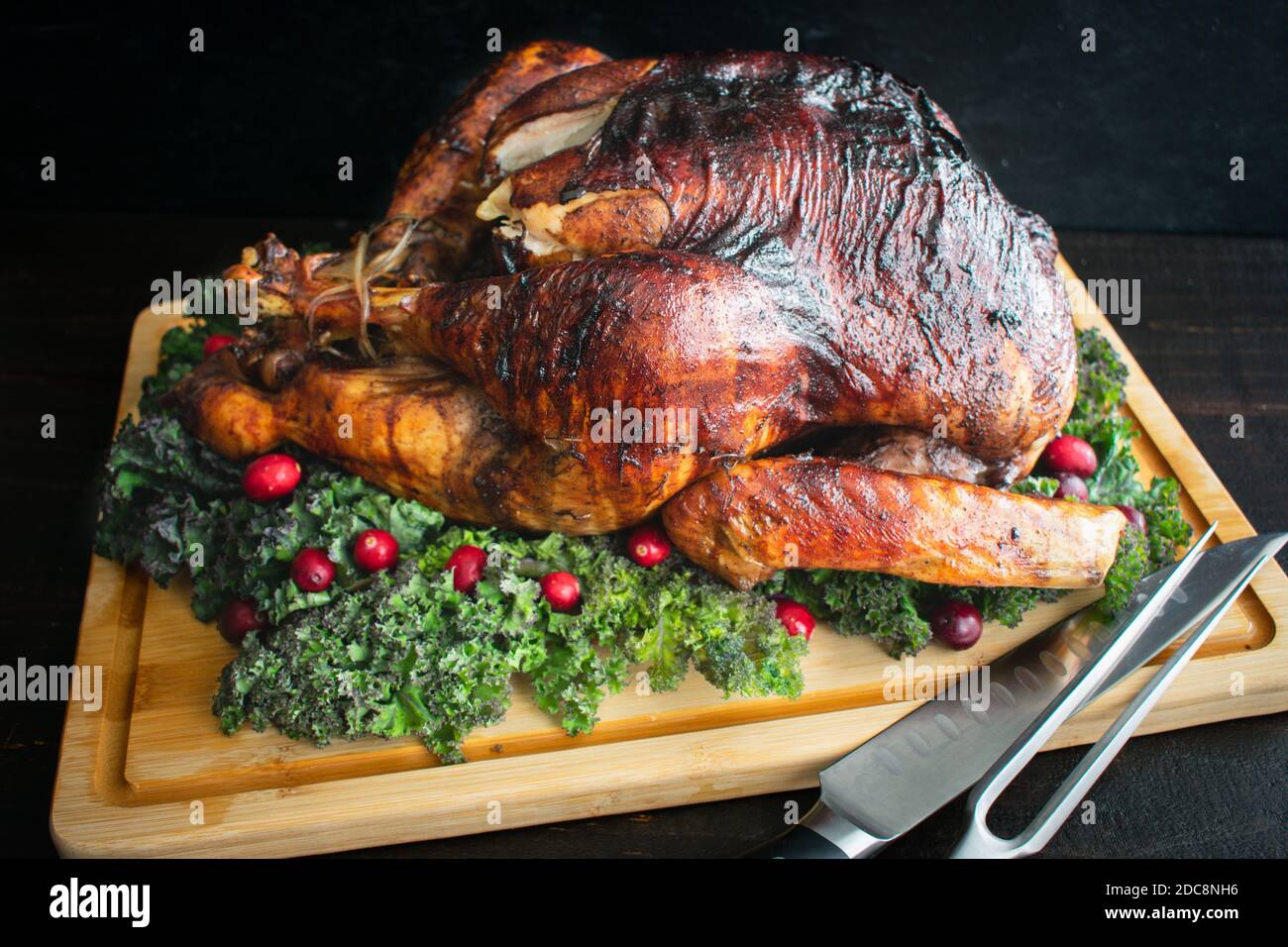 Truthahn auf einem Schnitzbrett braten: Ein ganzer truthahn auf einem Bambus-Schnitzbrett  garniert mit Grnkohl und Preiselbeeren Stockfotografie - Alamy