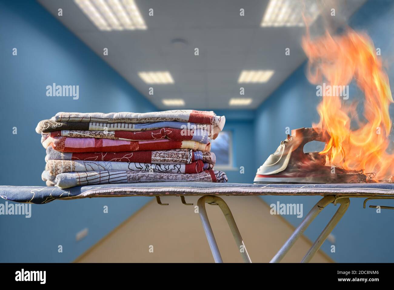 Hausbrand durch defekte Elektrogeräte, Flamme bis Kleidung Bügeleisen auf einem Bügelbrett. Stockfoto