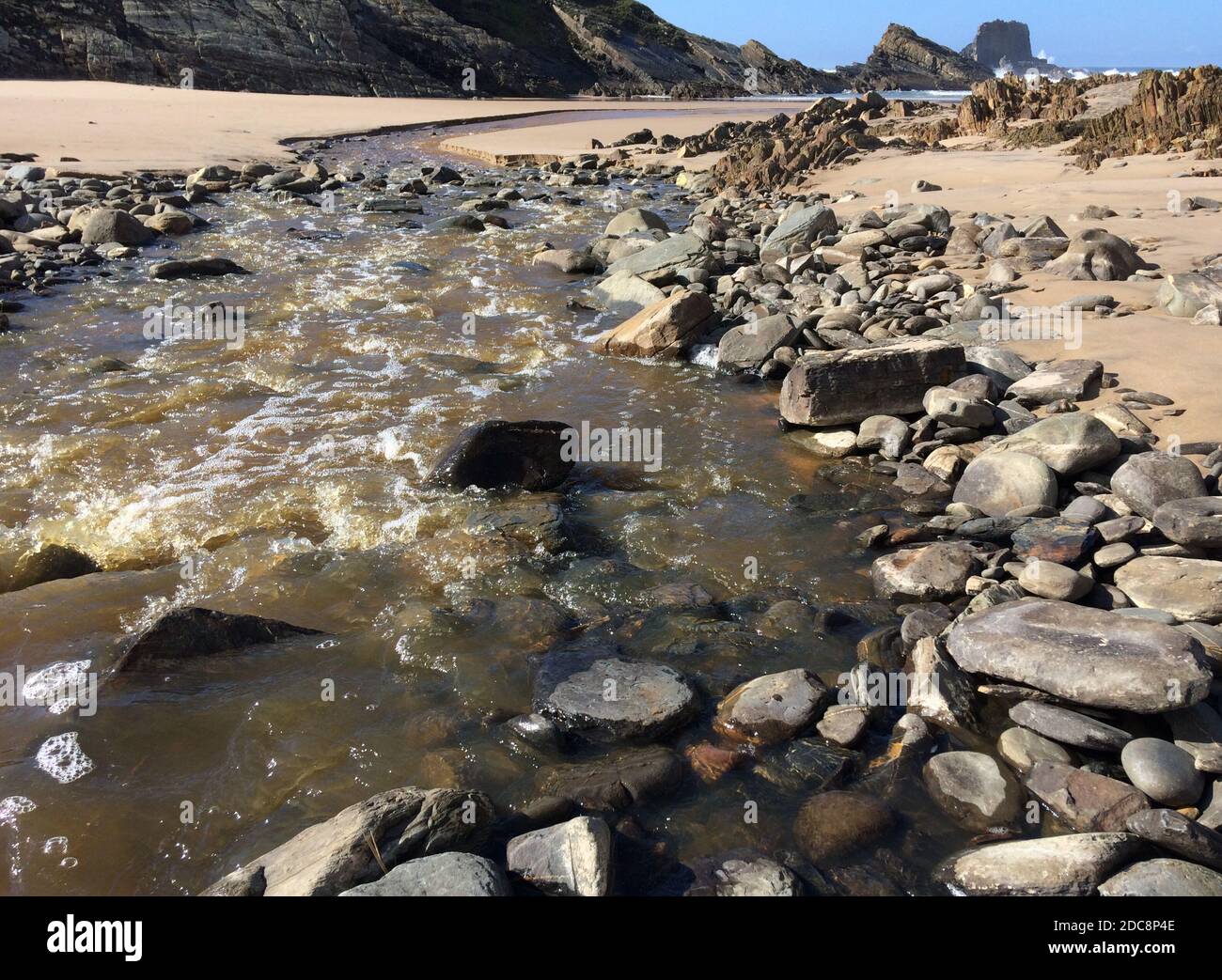 Kleiner Fluss fließt in den Ozean, schneller Strom fließt zum Meer, schöne Landschaft, erstaunliche Felsen Stockfoto