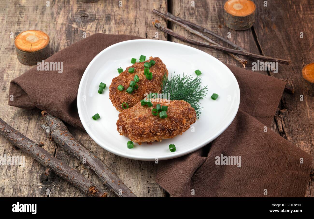 Fleischschnitzel in einem Teller auf einem natürlichen Holzhintergrund. Stockfoto
