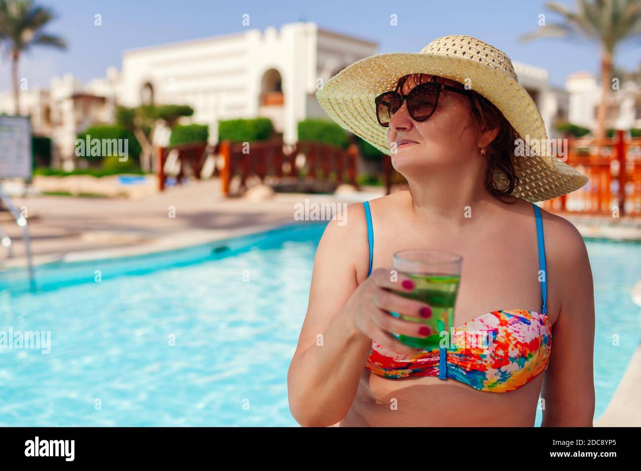 Ältere Frau in Bikini Drinks Cocktail im Hotel Swimmingpool. Tropischer Sommerurlaub. Exotisches Resort mit all inclusive Stockfoto Ältere Frau in Bikini Drinks Cocktail im Hotel Swimmingpool. Tropischer Sommerurlaub. Exotisches Resort mit all inclusive Stockfoto
