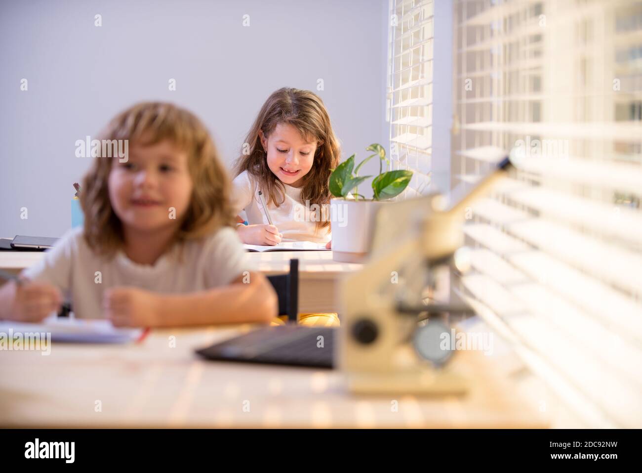 Kinder sitzen am Schreibtisch in der Schule Klassenzimmer und Schreibprüfung. SchuleKinder schreiben im Notizbuch während des Unterrichts. Stockfoto