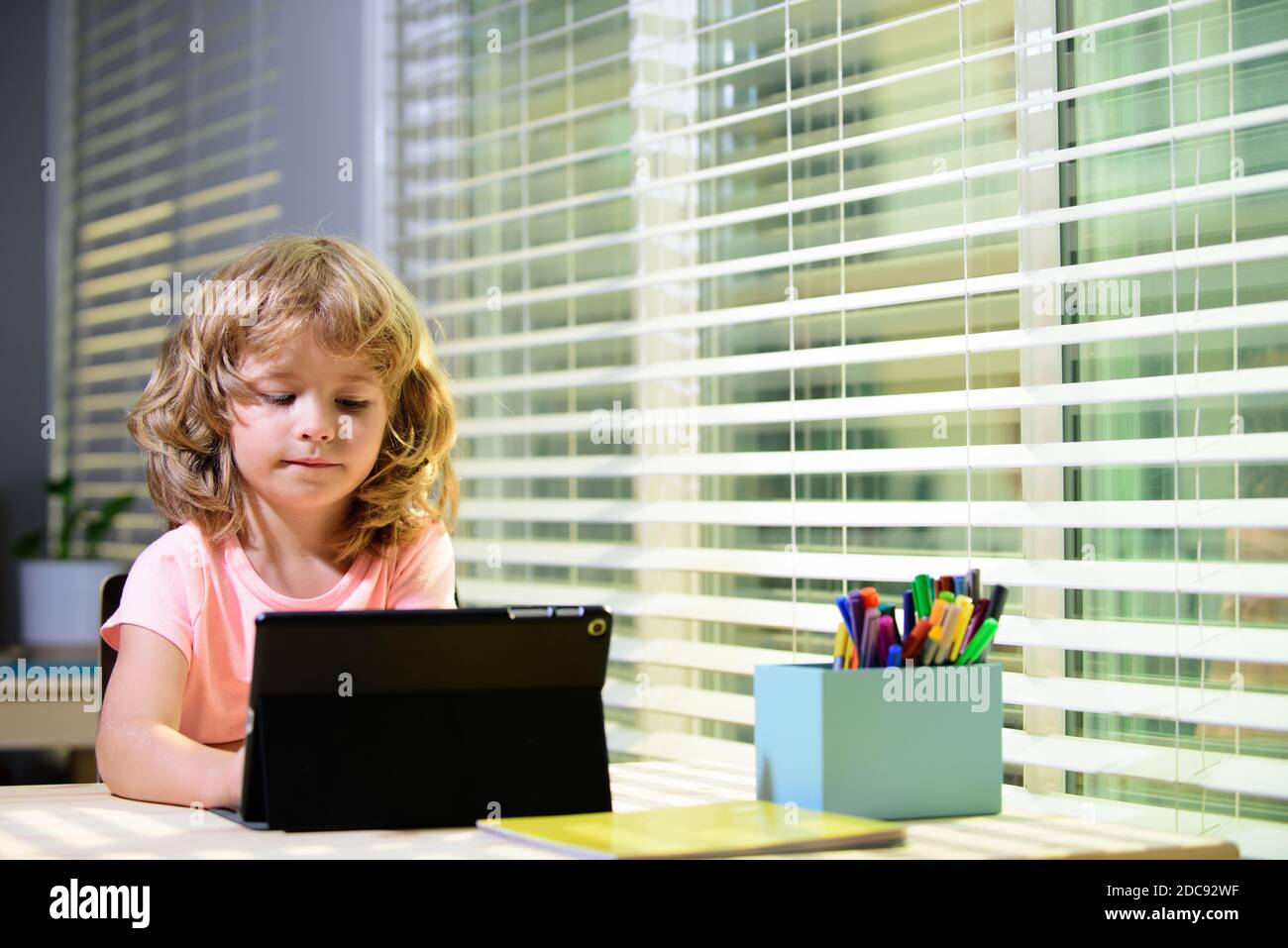 Nettes Kind Junge mit Tablet auf dem Schreibtisch zu Hause. Online-Bildungskonzept. Bildung für Kinder, Wissen. Stockfoto