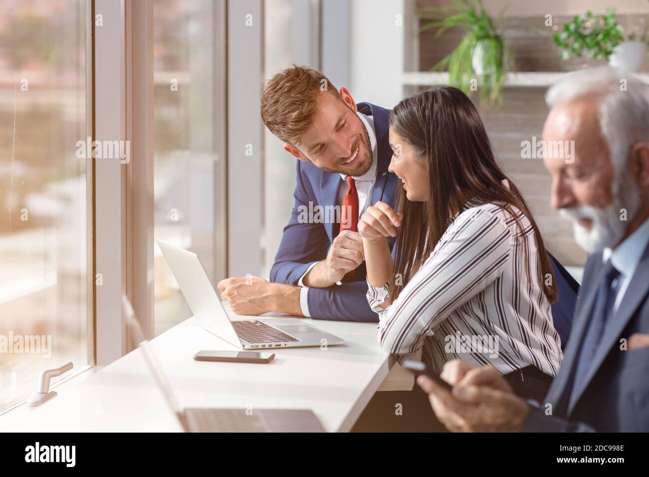 Porträt einer Gruppe von Kollegen aus verschiedenen Unternehmen, die als nächstes stehen Zum Fenster an einem Tisch in einem hellen modernen Büro Stockfoto
