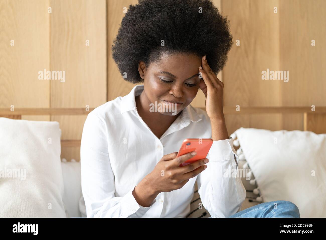 Leben Probleme, brechen mit Freund, schlechte Nachrichten, Herzschmerz. Besorgt afro-amerikanische Frau sitzt auf der Couch hält Handy lesen Nachricht unangenehm Stockfoto