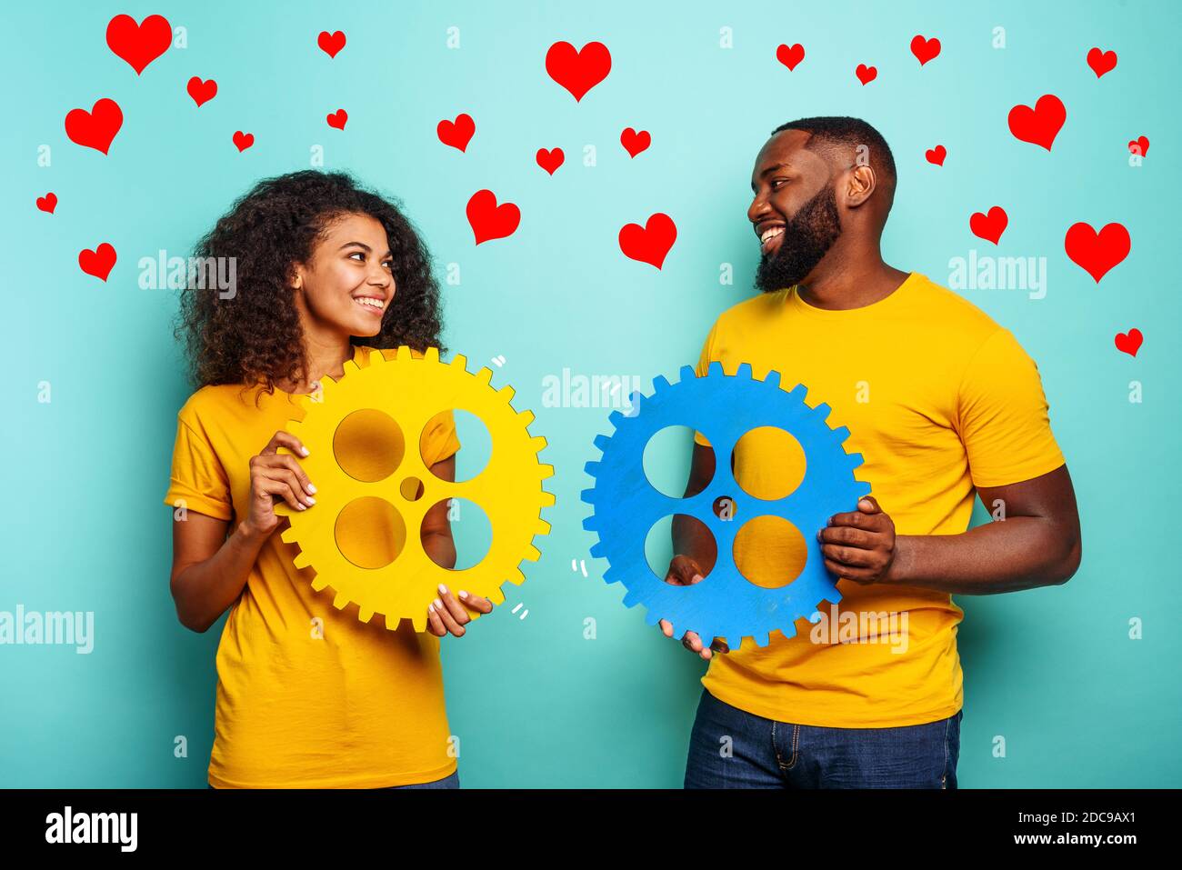 Paar mit Zahnrädern in der Hand über hellblauen Hintergrund. Konzept von Begegnung und Liebe Stockfoto