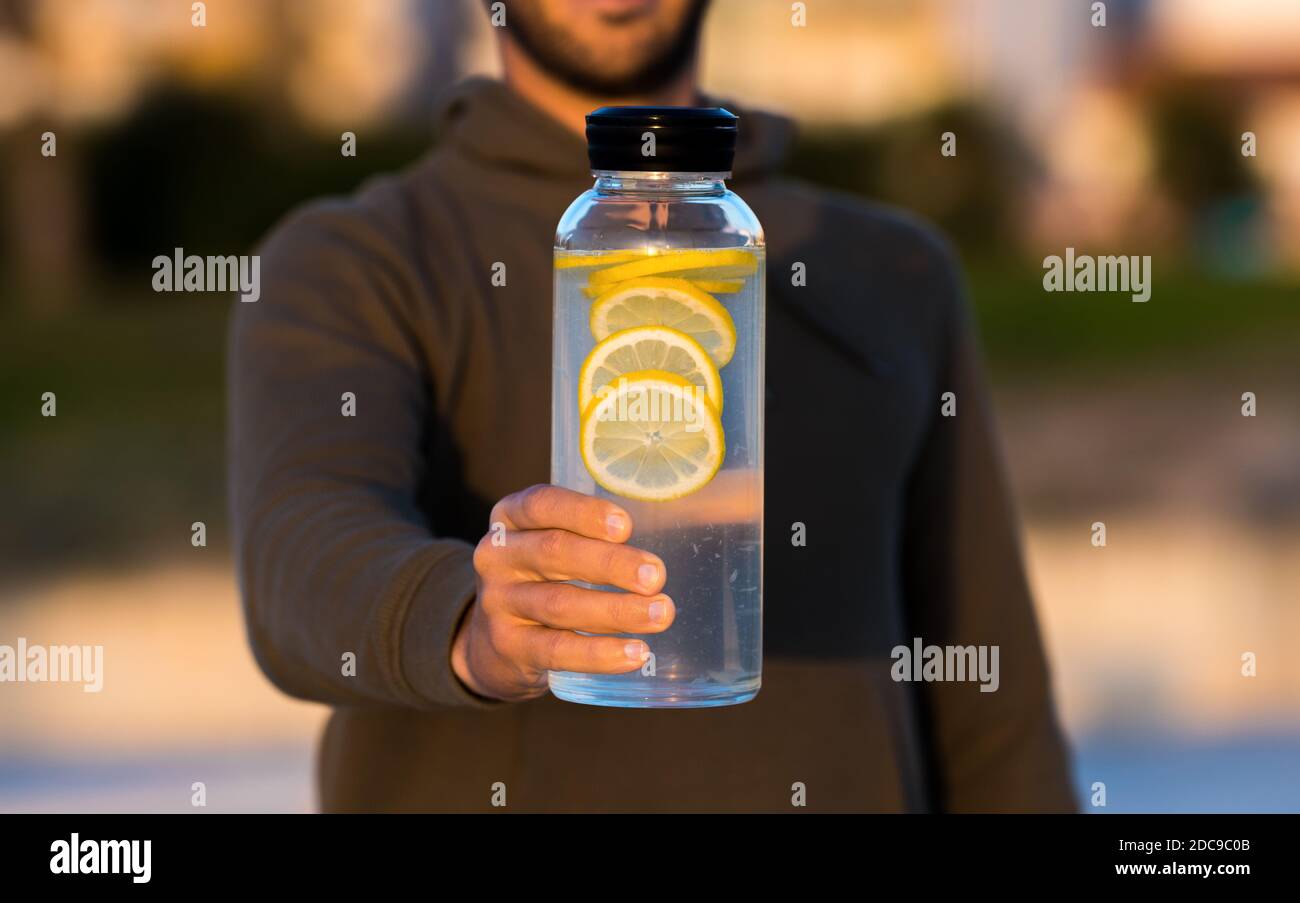 Mann, der eine Flasche frisches Zitronenwasser gibt. Gesunde Getränke, Ernährung und Entgiftung Konzept Stockfoto