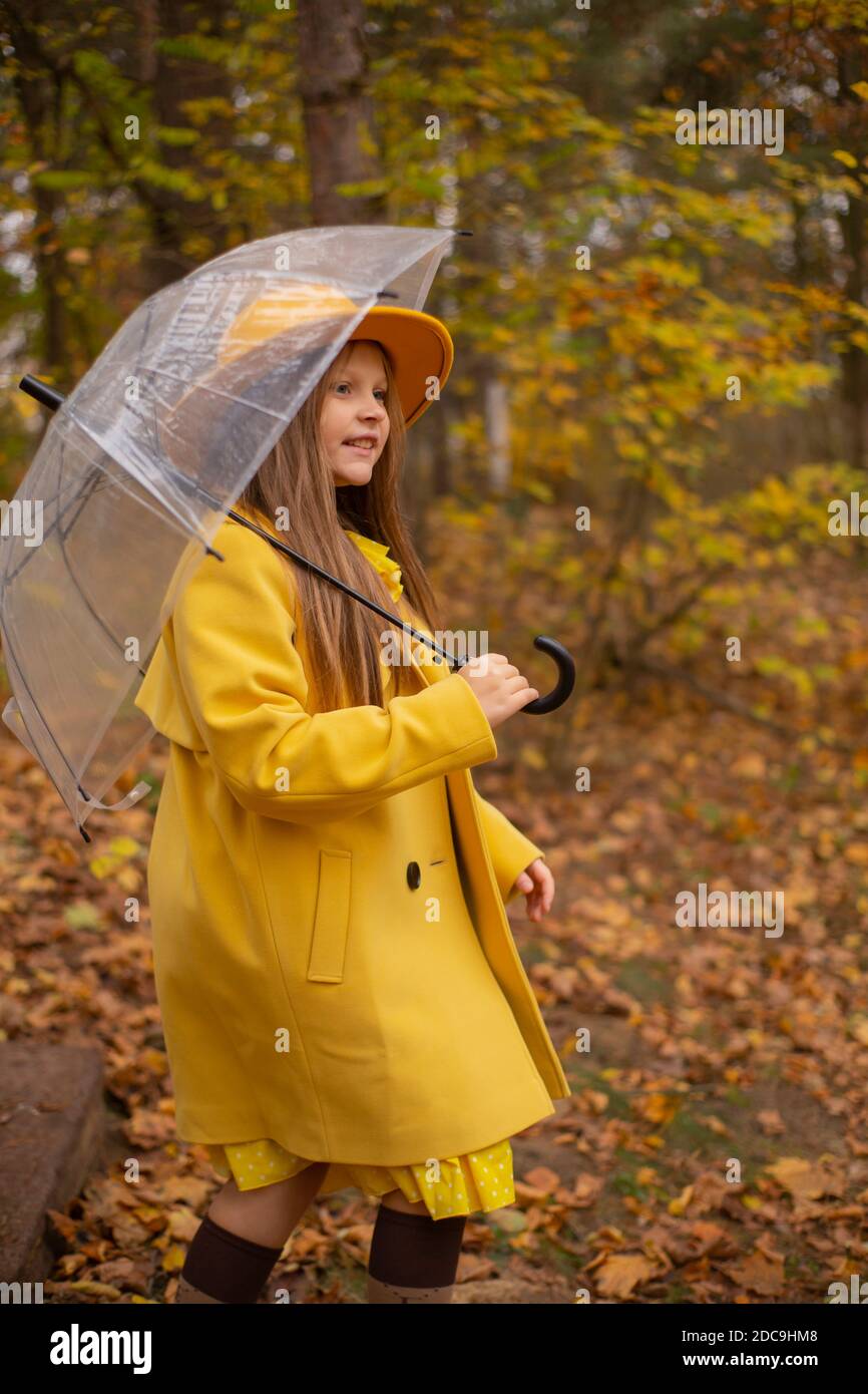 Nette schöne Teenager Brünette Mädchen in einem orangefarbenen Hut, Kleid  und Mantel zu Fuß mit einem transparenten Regenschirm. Gemütlichkeit,  Herbst Stockfotografie - Alamy