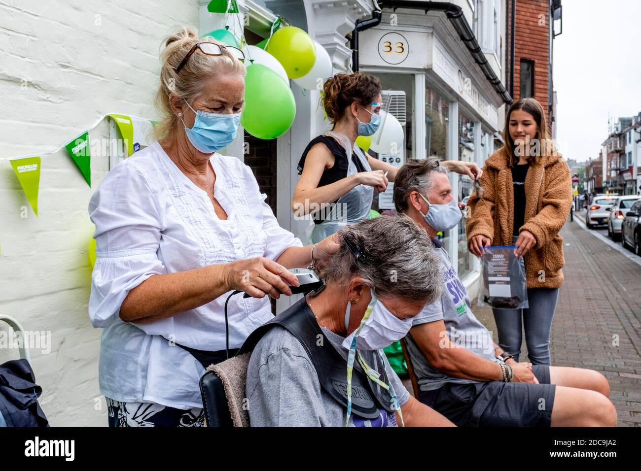 Menschen, die ihre Haare abschütteln, um Geld für die Macmillan Cancer Care Charity, High Street, Lewes, East Sussex, Großbritannien zu sammeln. Stockfoto
