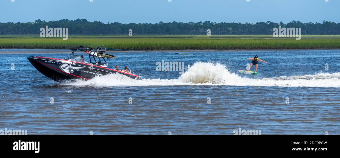 Foil Boarder rast über dem Wasser hinter einem Skiboot auf dem Intracoastal Waterway nahe der Nocatee Paddle Launch in Ponte Vedra Beach, Florida. (USA) Stockfoto
