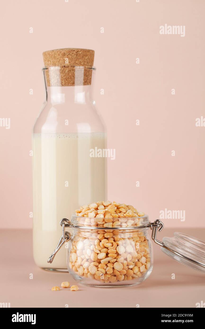 Erbsenmilch in der Flasche und Erbsen im Glas auf beigem Hintergrund. Glutenfreies, laktosefreies Produkt. Speicherplatz kopieren. Stockfoto