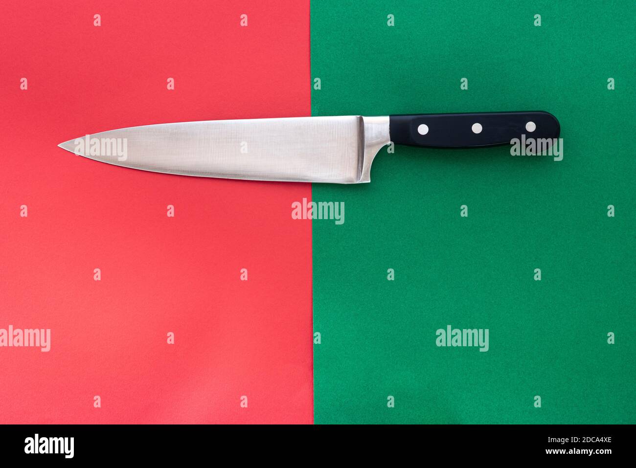 Großes Schnitzmesser auf einem geteilten roten und grünen Hintergrund. Stockfoto