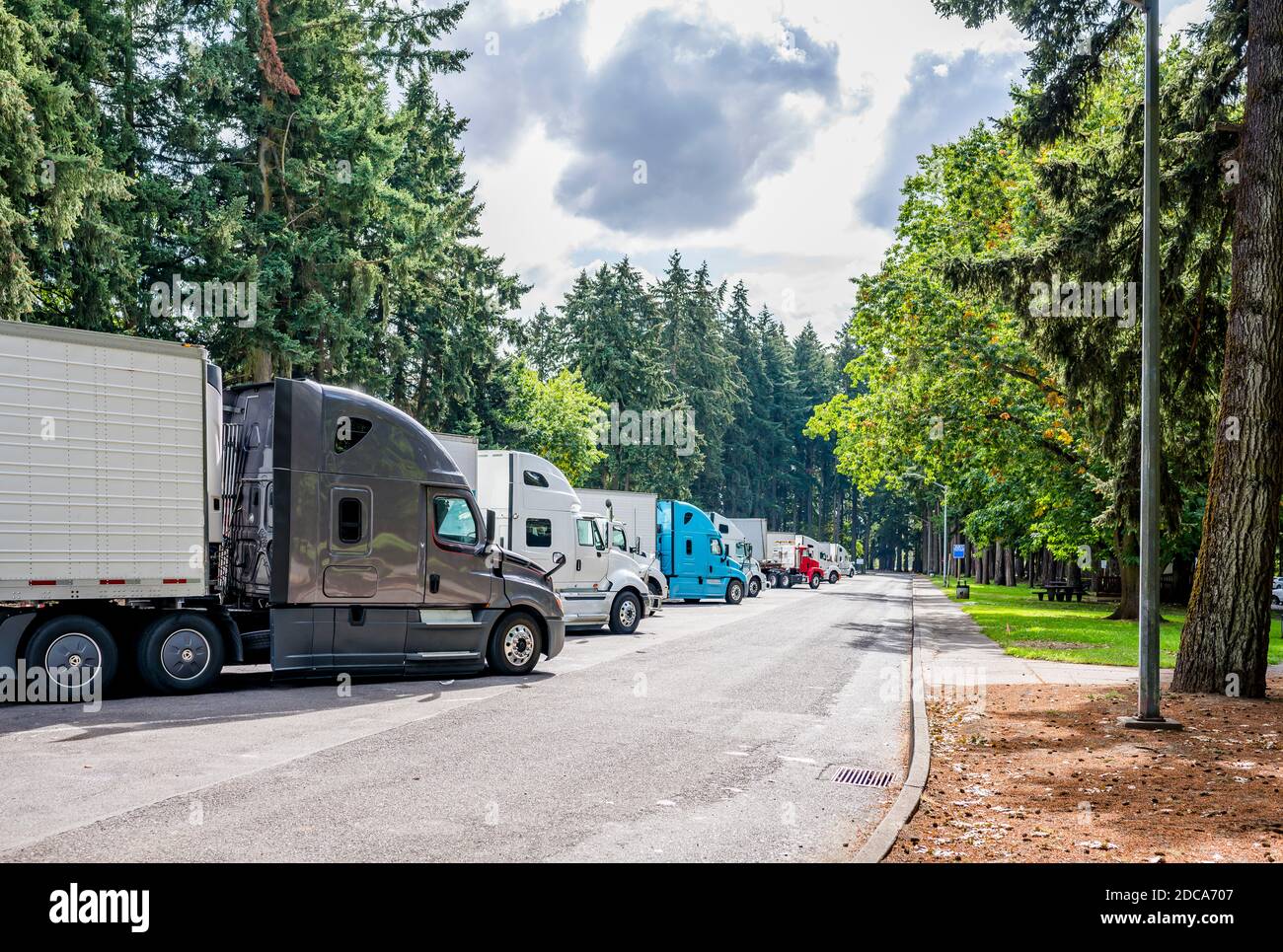 Verschiedene Marke und Modelle von großen Rigs semi-Trucks und Beladene Sattelanhänger stehen auf dem Parkplatz auf dem Rastplatz Grüner Wald für eine Pause und foll Stockfoto