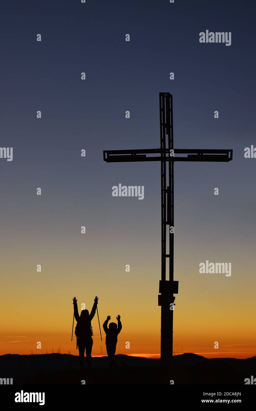 Mama mit Kind auf dem Berg in der Nähe der Kreuz heben ihre Arme im Sieg Stockfoto