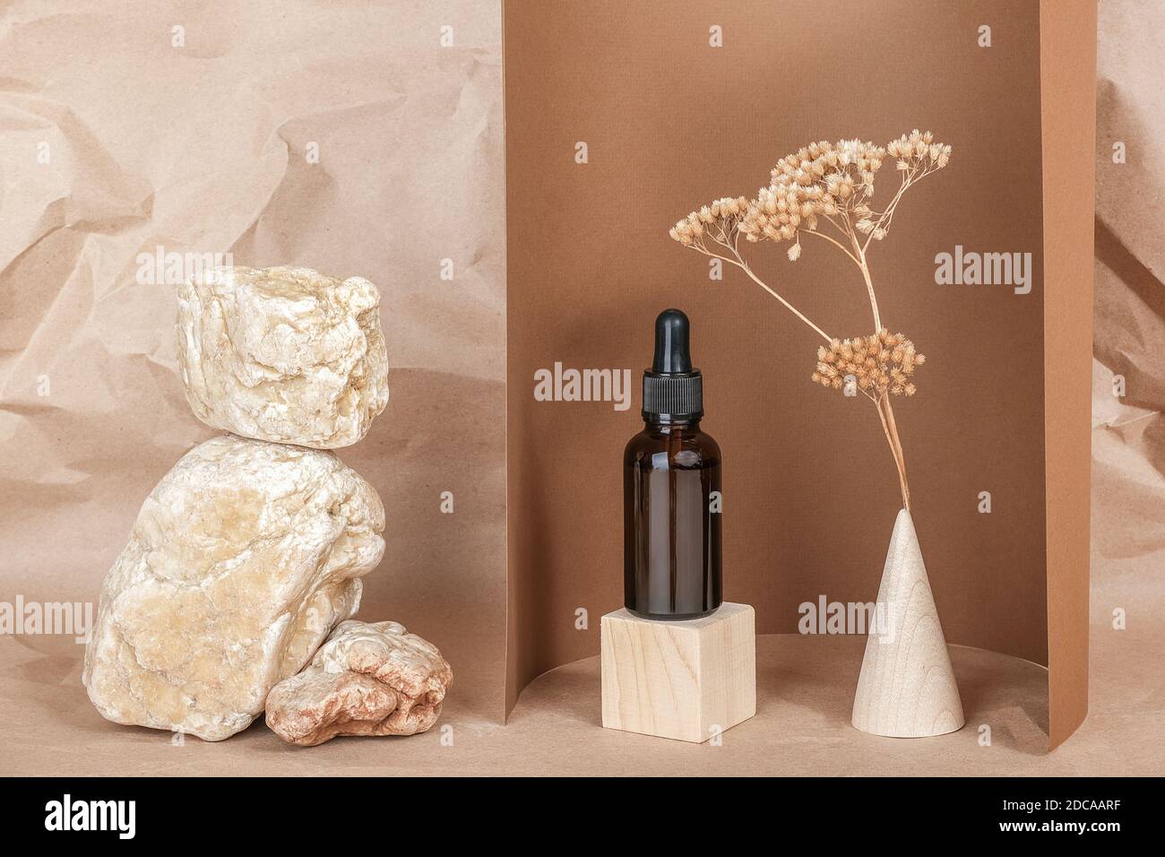 Serum, ätherische Öle oder flüssiges Kollagen in brauner Glasflasche mit Pipette auf geometrischen Holzformen, snone und getrocknete Blüten auf beige, braunes Backgr Stockfoto