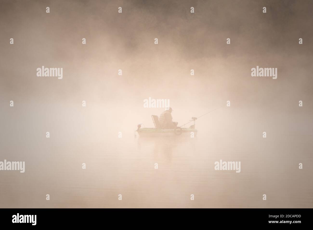 Silhouette eines Fischers in einem Raftingboot im dichten Nebel. Stockfoto