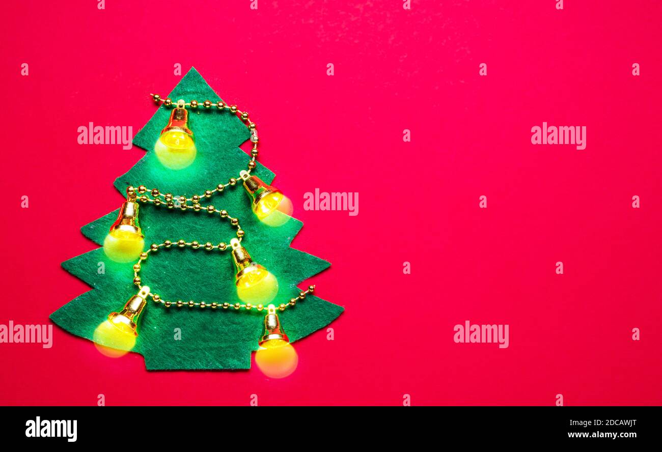 Handgefertigter Filz Neujahrsbaum auf rotem Papierhintergrund. Neujahr oder Weihnachten Hintergrund. Draufsicht. Stockfoto