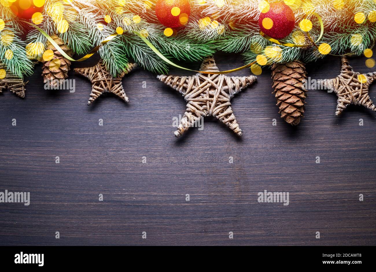 Schneebedeckter Tannenzweig mit Tannenzapfen und verschwommenen Weihnachtslichtern mit othe Dekor auf Holztisch. Weihnachten oder Neujahr Urlaub Hintergrund. Draufsicht. Stockfoto
