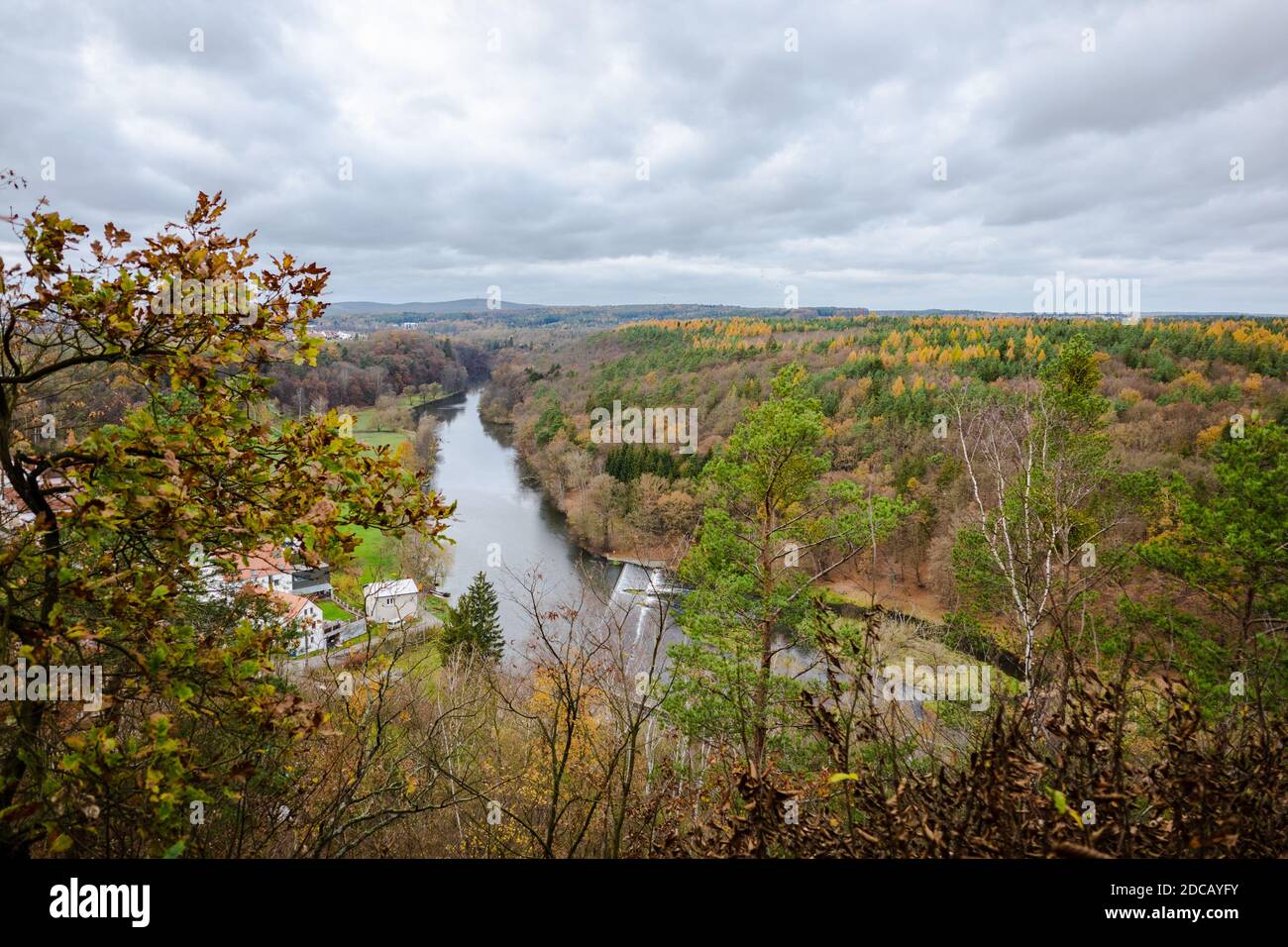 Der Blick auf den fernen Wald, wo die orangefarbenen und grünen Baumkronen gemischt sind. Dort fließt ein Fluss hinunter. Stockfoto