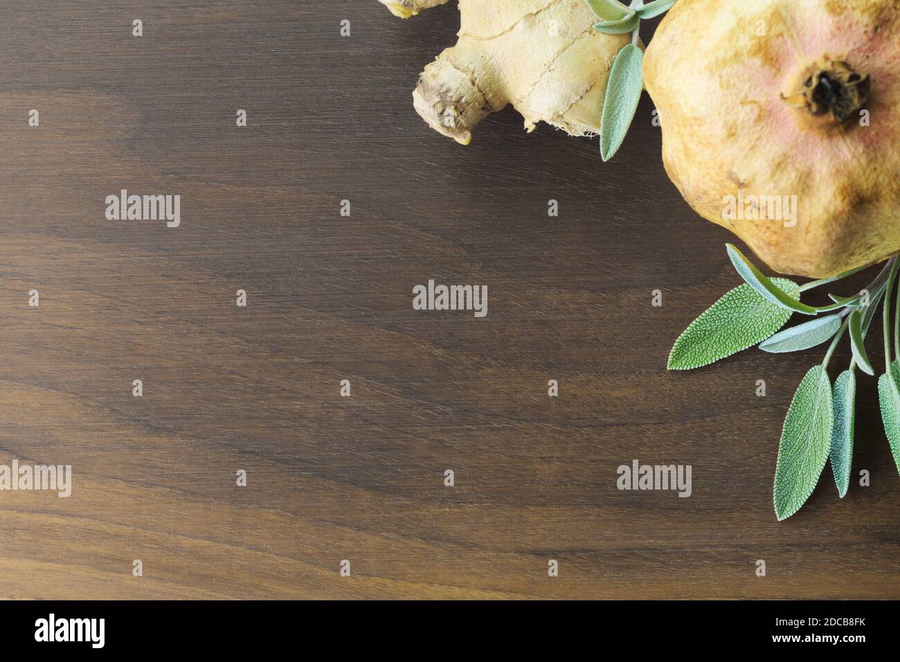 Close-up Holz Nussbaum Schneidebrett mit Ingwerwurzel, Ingwerscheiben und Salbeiblätter. Essen, Trinken, Gewürze und Gesundheitskonzepte Stockfoto