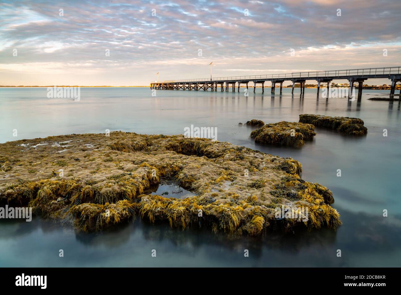 Eine lange Exposition der Korallenfelsen mit dem Robe Holzsteg im Hintergrund in Robe South beschichtet Australien am 9. November 2020 Stockfoto