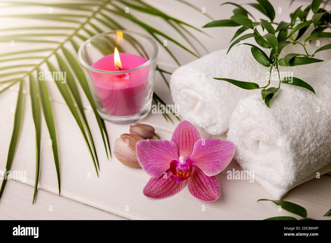 Spa-Handtücher mit Kerze und rosa Orchideenblume auf der Weißer Holztisch Stockfoto